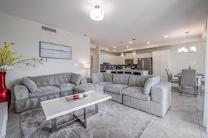 Uma sala de estar moderna com um sofá seccional, uma mesa de centro e uma área de jantar com mesa e cadeiras.
