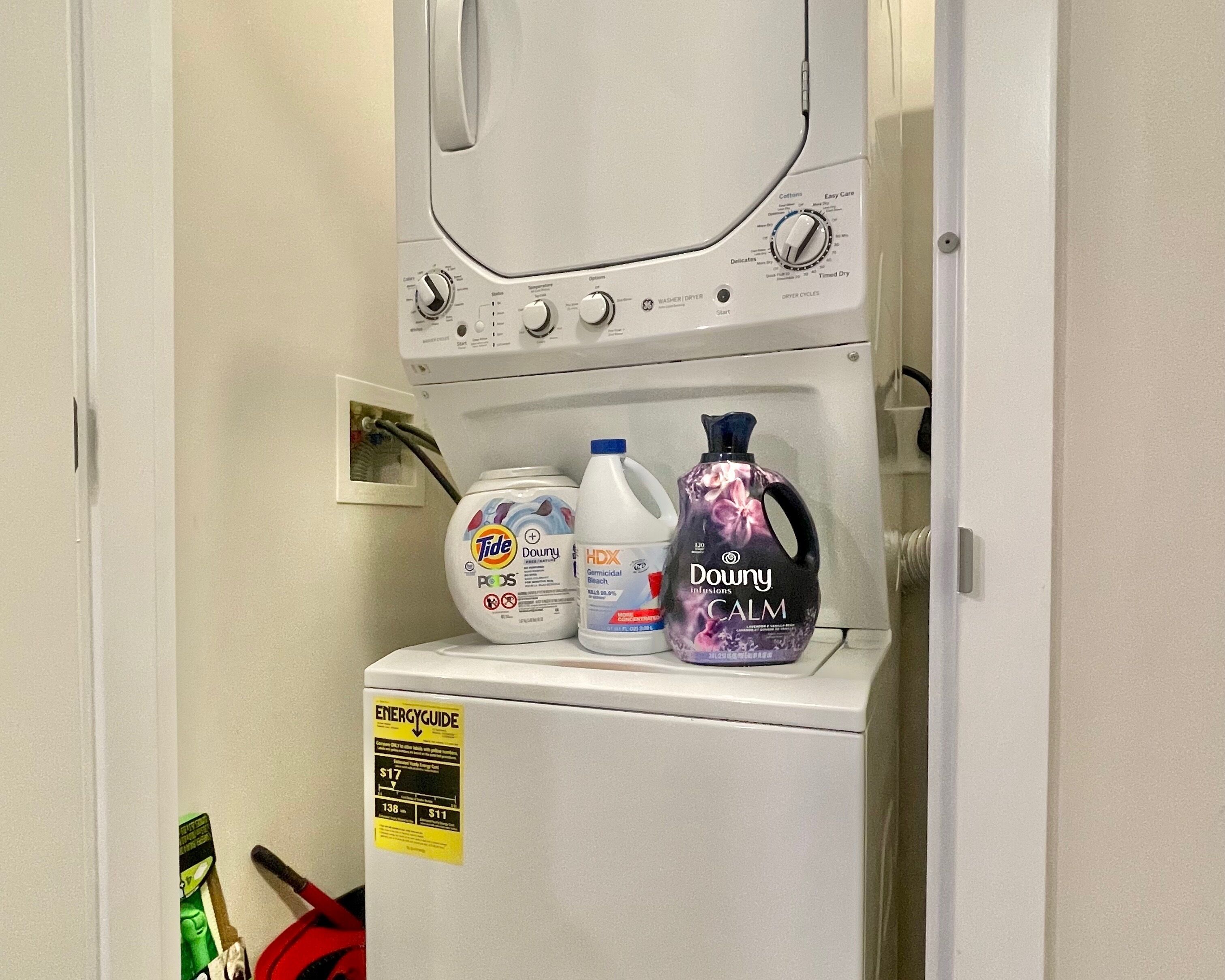 A laundry area with a washing machine, detergent bottles, and an energy guide sign.