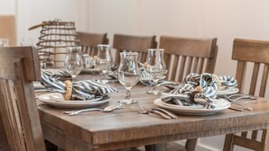 Une table de salle à manger en bois, mise avec des assiettes, des verres et des couverts.
