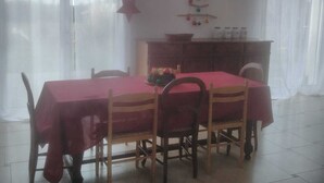 A dining area with a table set for four, wooden chairs, a red tablecloth, a star decoration, and a wall-mounted Christmas tree. - HOUSE Assérac, Pen Bé, quiet, Near beaches, 10m from coastal path (Assérac)