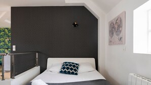 Habitació d'hotel moderna amb un llit, un capçal, un radiador i una finestra.