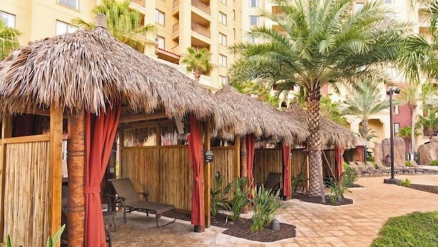 Ein Resort mit strohgedeckten Hütten, Palmen und einem gepflasterten Weg.