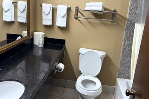 Ein Badezimmer mit Toilette, Waschbecken, Spiegel und Handtuchhalter mit mehreren Handtüchern.