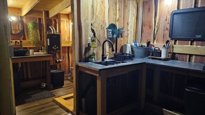 Una cocina rústica con paredes de madera, un lavaplatos, una estufa y diversos utensilios de cocina.