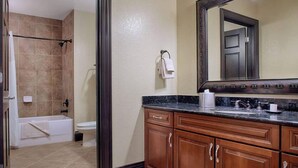 A bathroom with a bathtub, toilet, and a vanity with a mirror.