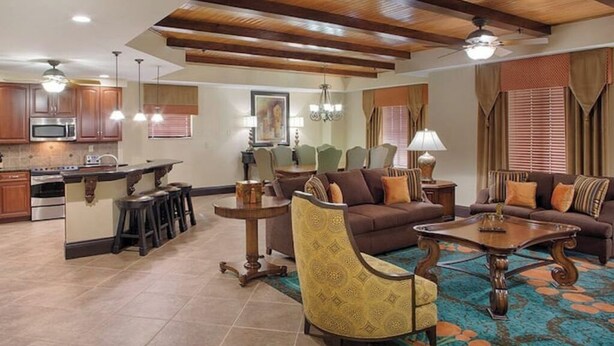 A spacious living area with a kitchen, wooden ceiling beams, and a dining set.