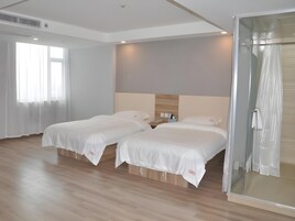 Habitación de hotel con dos camas, cabina de ducha de vidrio y un amplio ventanal con cortinas translúcidas.