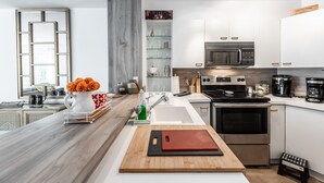 Une cuisine moderne avec des armoires blanches, une cuisinière en acier inoxydable et un plan de travail en bois.