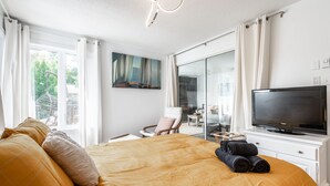 Une chambre d’hôtel avec un grand lit, un téléviseur à écran plat, un tableau au mur et une vue par la fenêtre.