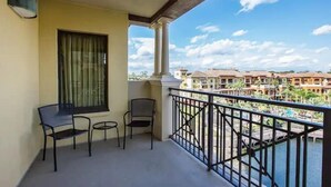 A balcony with two chairs and a table, overlooking a body of water and buildings. - SUPER HOSTS at Wyndham Bonnet Creek! (Lake Buena Vista)