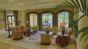 A spacious lobby with a large sofa, armchairs, and a coffee table. There are potted plants and lamps. - SUPER HOSTS at Wyndham Bonnet Creek! (Lake Buena Vista)