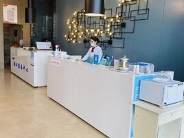 A reception desk with a modern design, including a geometric wall decoration and a digital screen.