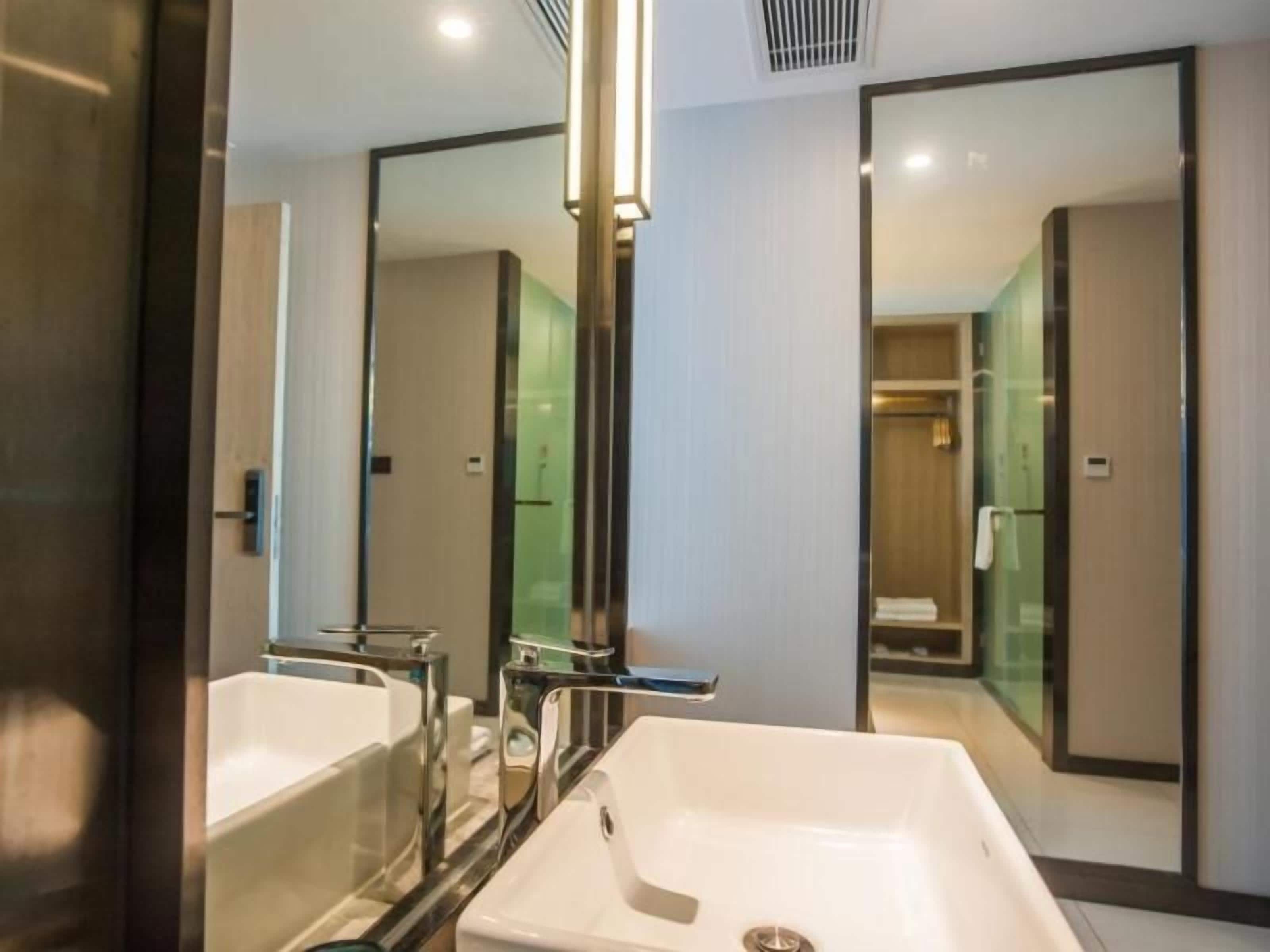 A modern bathroom with two sinks, a mirror, and a shower area.