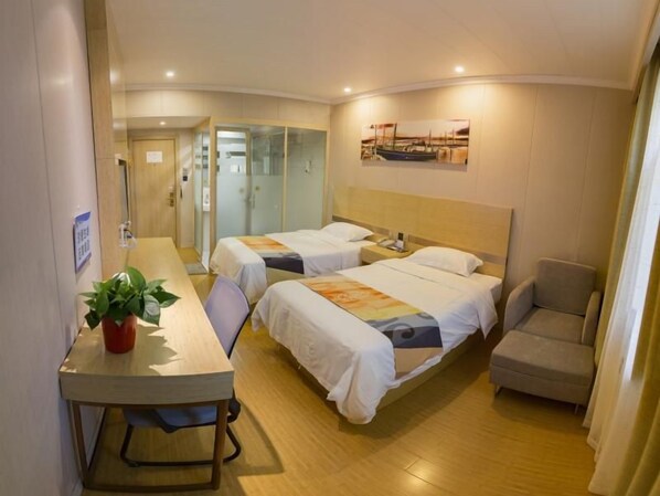 A hotel room with two beds, a desk, a chair, and a small table with a plant.