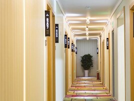 A hotel hallway with doors labeled with room numbers and directional signs.