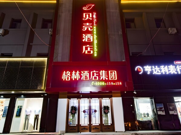 A hotel entrance with a prominent red sign, a glass door entrance, and a visible contact number. - Shell Taian Dongping County Xishan Road Ruyuan City Square Dongyue Plaza (Tai'an)