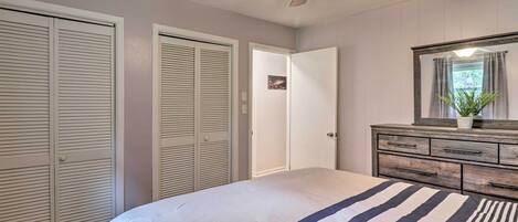 A bedroom with a bed, a ceiling fan, a dresser, and a mirror.