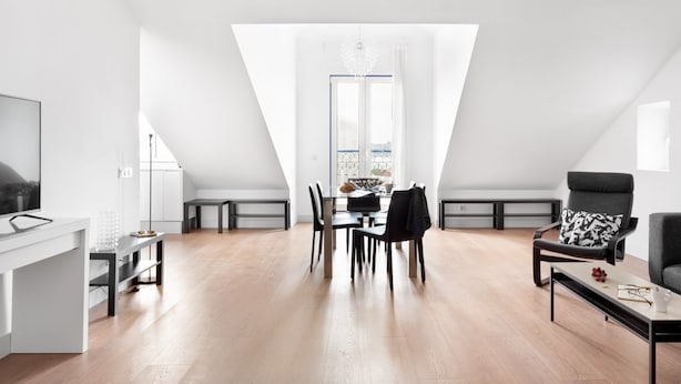 A modern, open-plan living and dining area with a high ceiling and skylight, a flat-screen TV, and a dining table set for four. - JOIVY Modern flat w/river view near Bica Elevator (Lisboa)