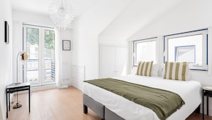 A bedroom with a large bed, a desk, a chair, and a window with a view of the outside. - JOIVY Modern flat w/river view near Bica Elevator (Lisboa)