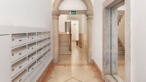 A hallway with a row of filing cabinets on the left, a staircase in the center, and a door on the right. - JOIVY Modern flat w/river view near Bica Elevator (Lisboa)