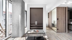 Un intérieur moderne avec une table basse en verre, une bibliothèque intégrée et une vue sur la ville grâce à de grandes fenêtres.