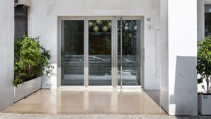 Une entrée moderne avec une porte en verre, une plaque portant le numéro « 42 » et des plantes en pot.