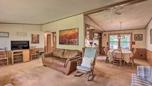 A spacious living room with a brown leather sofa, a rocking chair, and a dining table with chairs. There is a television and a painting on the wall. - Charming Burdett Home with Grill, Gazebo + Yard (Burdett)
