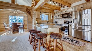 A log cabin interior with a kitchen, dining area, and bar stools. - Breck Cabin/ Mins from Town & Lifts/ Hot Tub (Breckenridge)
