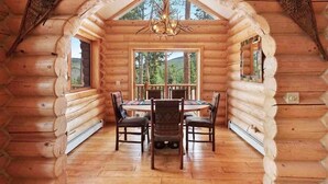 A log cabin with a central dining area featuring a round table and chairs, large windows, and a chandelier. - Breck Cabin/ Mins from Town & Lifts/ Hot Tub (Breckenridge)