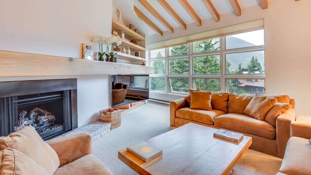 A modern living room with a fireplace, a large window, and a cozy seating area.