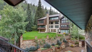 A multi-story building with a stone facade, a swimming pool, and a well-maintained lawn.