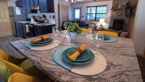 A dining area with a large granite table set for four, surrounded by yellow chairs. - MNT VIEWS! Private HOT TUB and Wrap Around Porch! Minutes to PF and Gatlinburg! (Sevierville)