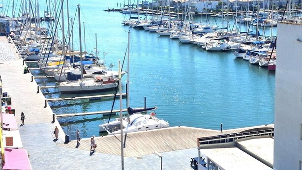 A marina with numerous boats docked, a pier with people walking, and a cityscape in the background. - BEL APPARTEMENT AVEC VUE SPLENDIDE (LE CAP D AGDE)