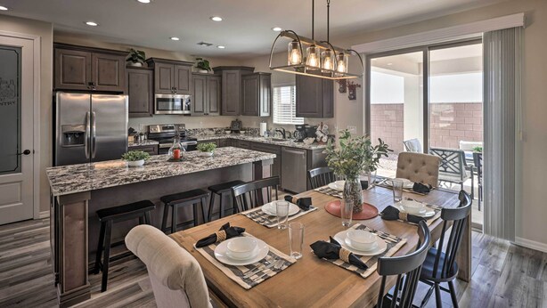 A modern kitchen with granite countertops, stainless steel appliances, and a dining area with a wooden table and bar stools. - Arizona Home: 3 Mi to CO River, Snowbirds Welcome (Bullhead City)