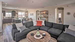 A modern living room with a sectional sofa, a coffee table with decorative items, and a ceiling fan. - Arizona Home: 3 Mi to CO River, Snowbirds Welcome (Bullhead City)