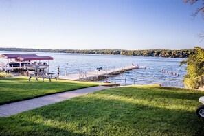 A lakeside dock with a boat, picnic tables, and a grassy area. - Cozy House perfect to enjoy the lake with Beach & Boat launch 2 minutes drive. (Lake Geneva)