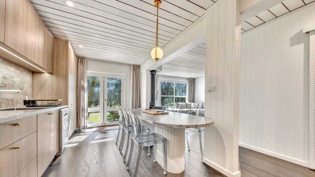 Une cuisine moderne dotée d’un îlot central, de meubles en bois et d’une grande fenêtre qui laisse entrer la lumière naturelle.