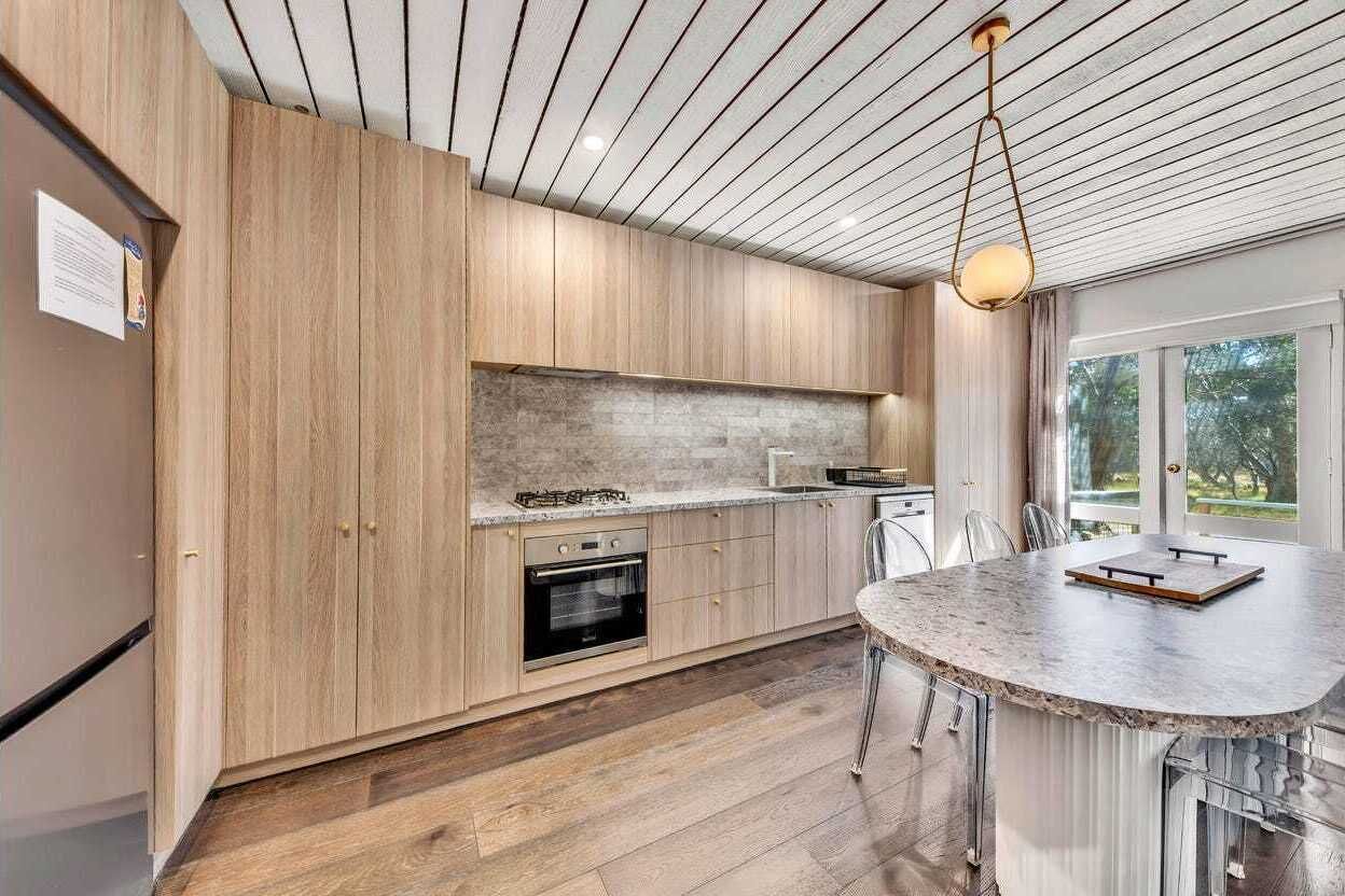 A modern kitchen with wooden cabinets, a granite countertop, and a built-in oven.