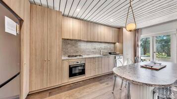 A modern kitchen with wooden cabinets, a granite countertop, and a built-in oven.