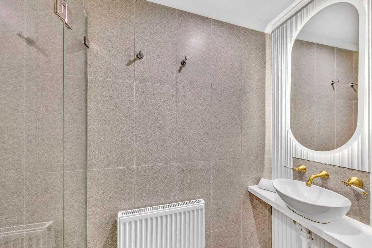 Ein Badezimmer mit einem weißen Waschbecken, goldenen Armaturen und einem großen Spiegel.