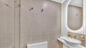 Ein Badezimmer mit einem weißen Waschbecken, goldenen Armaturen und einem großen Spiegel.