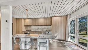 Une cuisine moderne dotée d’un îlot central, de chaises transparentes et d’un luminaire suspendu.