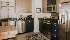 A modern kitchen with dark cabinets, stainless steel appliances, and a granite countertop. - 3BR/2BA w/GOLF CART!! Close to Beach & Downtown Ocean Springs! Southern Exposure (Ocean Springs)