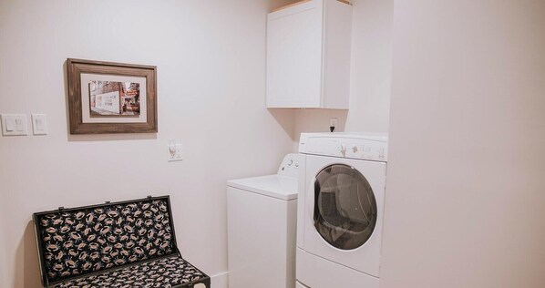 Une buanderie équipée d’un lave-linge, d’un sèche-linge et d’un banc de style vintage.