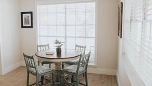 A dining area with a round table, four chairs, a potted plant, and a framed picture on the wall. - 3BR/2BA w/GOLF CART!! Close to Beach & Downtown Ocean Springs! Southern Exposure (Ocean Springs)