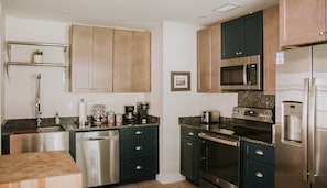 Una cocina moderna con armarios oscuros, electrodomésticos de acero inoxidable y encimera de granito.