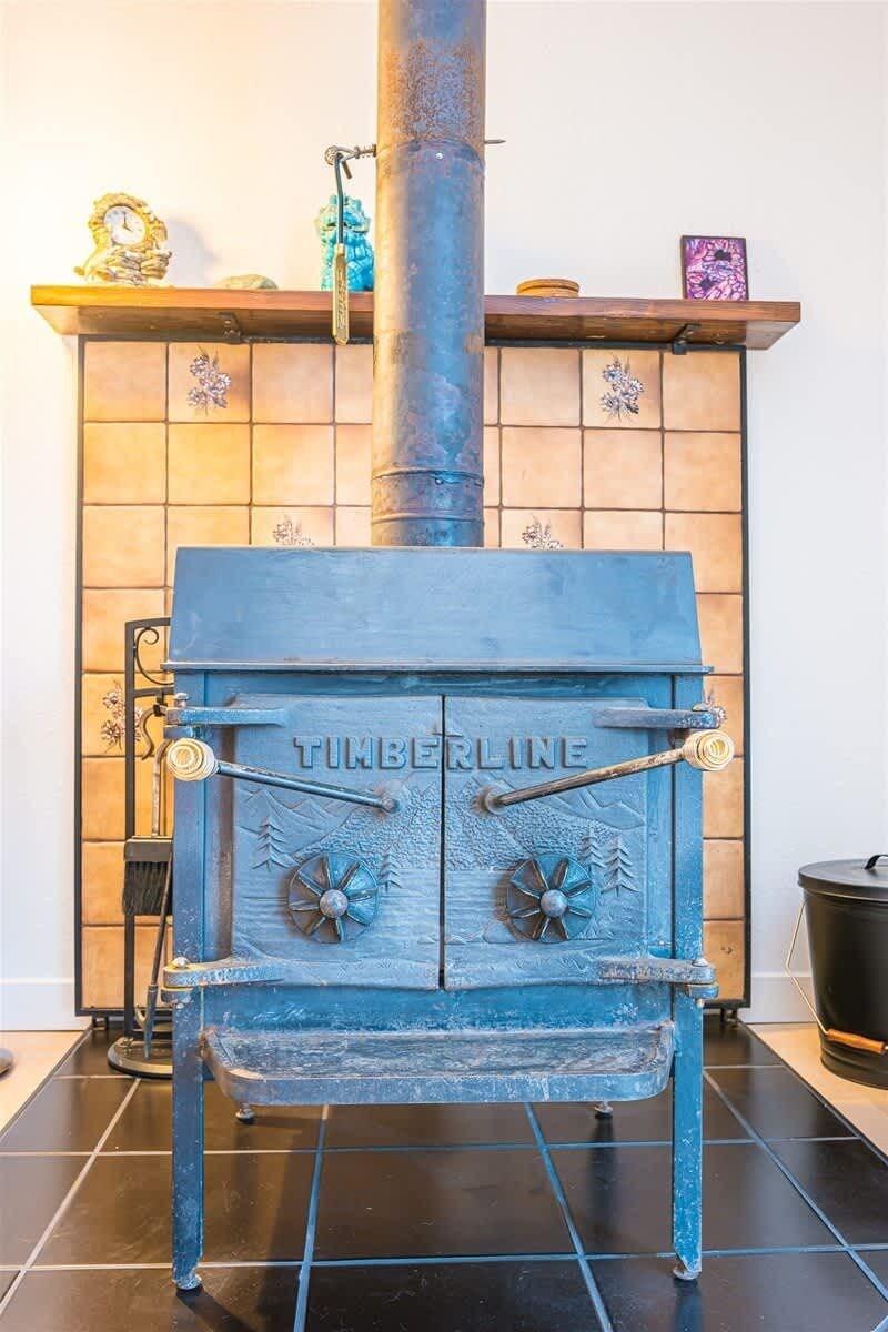 A vintage TIMBERLINE wood stove with a chimney, set against a tiled wall.
