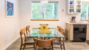 Uma cozinha moderna com uma mesa de jantar de vidro, cadeiras de madeira e um forno embutido.