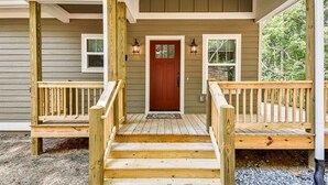 A wooden front porch with a red door, two windows, and a bench. - Dream Ridge | Ellijay, GA (Ellijay)