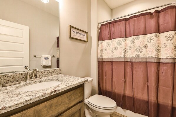 A bathroom with a sink, toilet, and shower curtain.